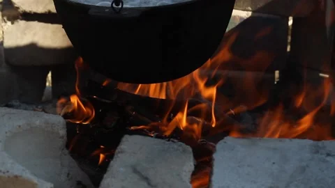 Fire burns in a brick hearth under a black cauldron Stock Footage 130828957