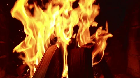 Fire burns brightly inside a fireplace as logs crackle and spark during the Stock Footage 344318202