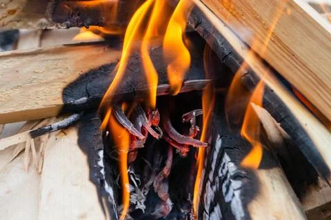 A fire burns in a campfire with a red fire in the background. Stock Photos