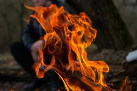 A fire burns in a campfire with a red fire in the background. Stock Photos