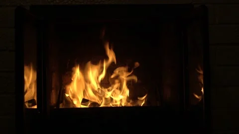 A fire burns in the dark in the fireplace. Bright orange flames are reflected Stock Footage 124114717