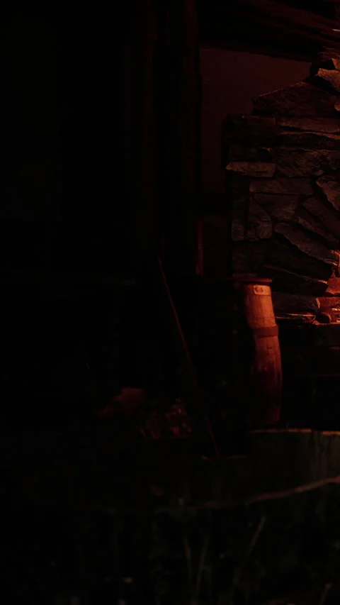 Fire burns in the hearth while shadows dance around a rustic stone wall Stock Footage 339042465