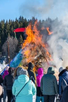 Fire burns straw doll during Maslenitsa festival. People watch fire Stock Photos