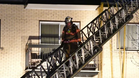 Fire Chief descending ladder during night Stock Footage 114648435