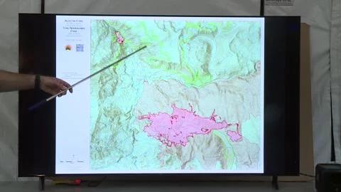 FIRE CHIEF USING POINTER ON A MAP WHERE THE FIRE HAS BEEN CONTAINED Stock Footage 345276774