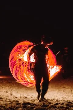 A fire dancer moves balls with ignited fired creating patterns in a long ex.. Stock Photos