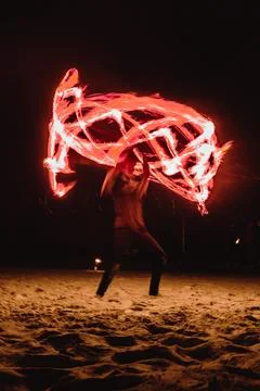A fire dancer moves balls with ignited fired creating patterns in a long ex.. Stock Photos