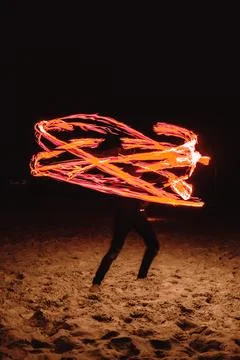 A fire dancer moves balls with ignited fired creating patterns in a long ex.. Stock Photos