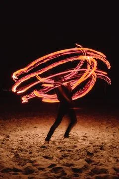 A fire dancer moves balls with ignited fired creating patterns in a long ex.. Stock Photos