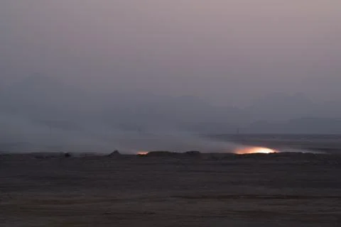 Fire in the desert in the evening. In the background, mountains Stock Photos