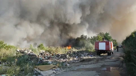 Fire in the dump, burning garbage and low vegetation, big smoke rising Stock Footage