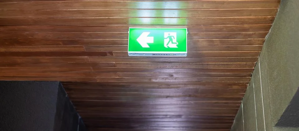 Fire Emergency exit sign on the wall background inside building. Safety conce Stock Photos