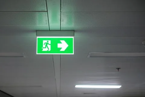 Fire Emergency exit sign on the wall inside building at subway train statio.. Stock Photos