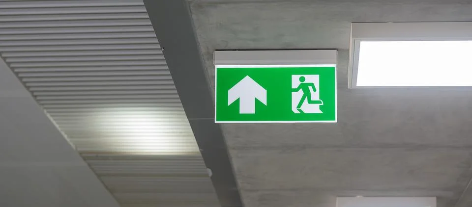 Fire Emergency exit sign on the wall inside building at subway train statio.. Stock Photos
