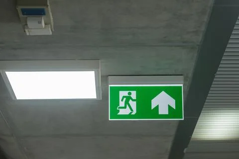 Fire Emergency exit sign on the wall inside building at subway train statio.. Stock Photos