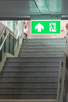 Fire Emergency exit sign on the wall inside building at subway train statio.. Stock Photos