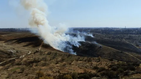 Fire in an empty field near the city. Strong smoke from burning place. Aeria Stock Footage 128104010