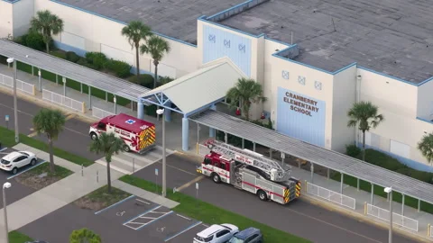 Fire engine and ambulance visible at public school entrance as responders treat Stock Footage 315303921