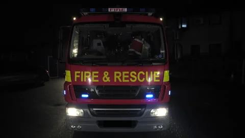 Fire engine and rescue truck flashing blue lights at night. UK Stock Footage 330399158