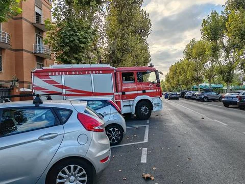 A fire engine parked in a herringbone pattern between cars along the street Stock Photos