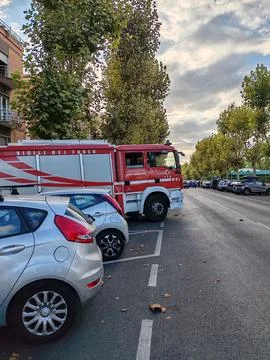 A fire engine parked in a herringbone pattern between cars along the street Stock Photos