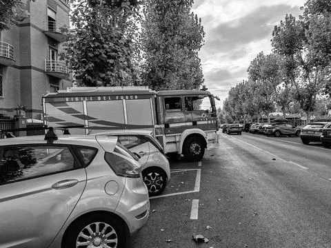 A fire engine parked in a herringbone pattern between cars along the street Stock Photos