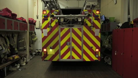 Fire engine truck leaving the station for an emergency call at night. UK Stock Footage 330399369