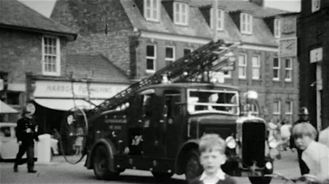 Fire engines on a fire call in a town centre in England on old B&W film Stock Footage