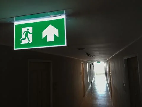 Fire escape the building, condo.A rather dark corridor and fire exit sign lig Stock Photos