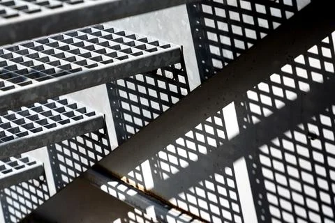 A fire escape with its openwork steps forms graphic elements of triangles. Foto stock