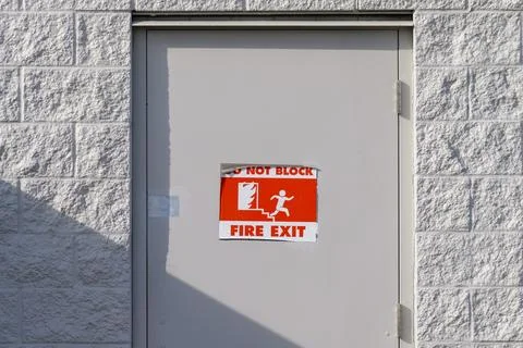 Fire exit door with warning sign on a gray wall Stock Photos