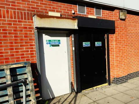 Fire exit doors on red brick wall in Manchester UK with keep clear signs an.. Stock Photos