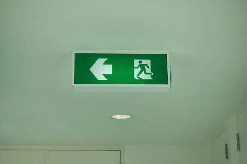 Fire exit sign on ceiling in office. Stock Photos