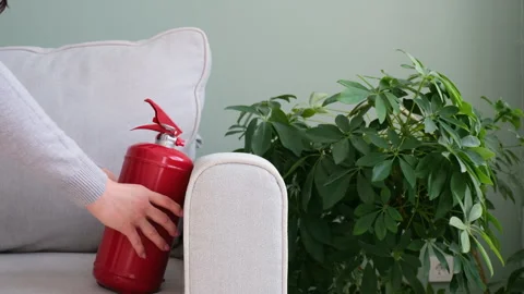 The fire extinguisher is on the gray sofa in the room. Fire safety at home Stock Footage 303958409