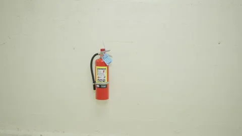 A fire extinguisher placed on a white wall . Stock Footage 244400234