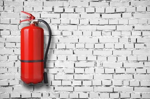Fire extinguisher on white brick wall 库存照片