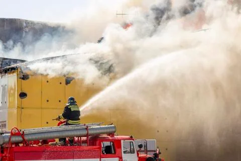 Fire extinguishing. Fire engine. A firefighter directs a stream of water at a Stock Photos