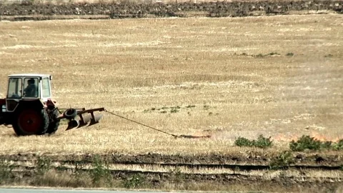 Fire on the field - man on tractor burning wheat stubble 動画素材 73294758