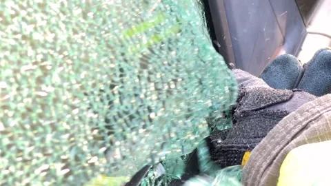 Fire fighter breaking car driver side window with tool slow motion Stock Footage 286765714