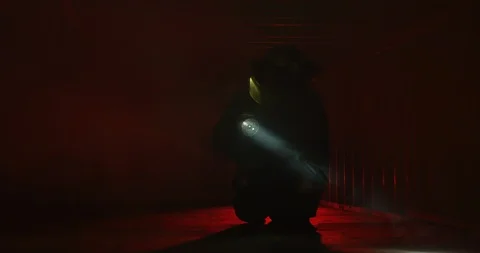 Fire Fighter crawls in confined space shining flashlight through smoke lookin Stock Footage 107027907