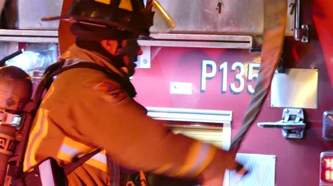 Fire fighter gathering fire hose to deploy Stock Footage 56873527