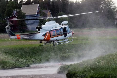 Fire fighter helicopter hovering over a small river and filling a bucket Stock Photos