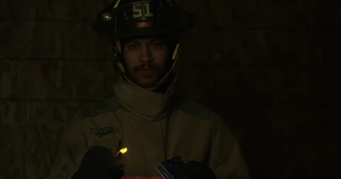 Fire Fighter lights match and looks towards camera - slow motion Stock Footage 107002596