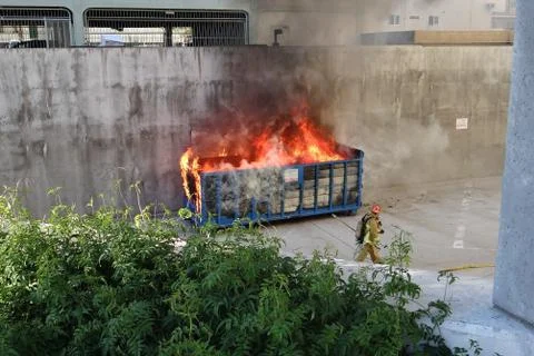 Fire Fighter Preparing To Extinguish A Fire Burning In A Commercial Dumpster Stock Photos