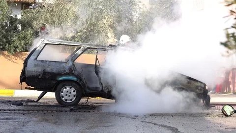 Fire Fighter Puts Water Hose On Burning Car Stockbeeldmateriaal 86590455