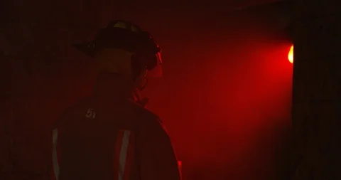 Fire Fighter walks through doorway of smokey red room Stock Footage 108819104