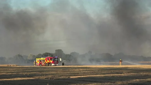 Fire fighters putting out flames in a field in Ardleigh, Essex, UK. Stock Footage 138115056