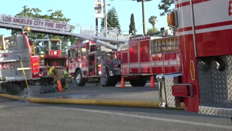 Fire fighters responding to burning building &amp; fire truck on standby Stock Footage 209724014