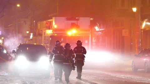 Fire fighters walking towards camera with smoke and firetruck with lights Stock Footage 49696179