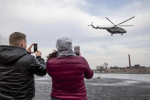 A fire-fighting helicopter draws water from a river Stock Photos
